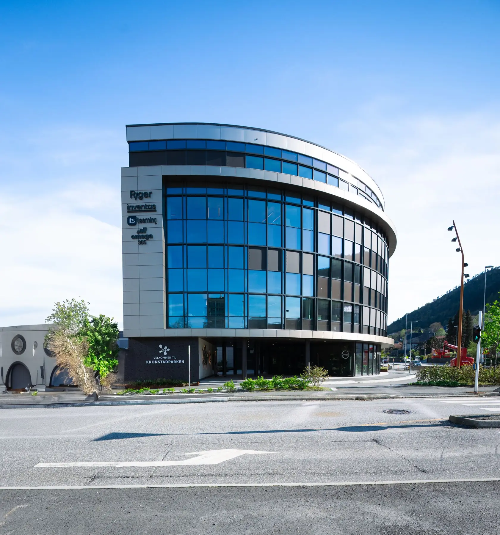 Curved glass commercial building under a clear blue sky